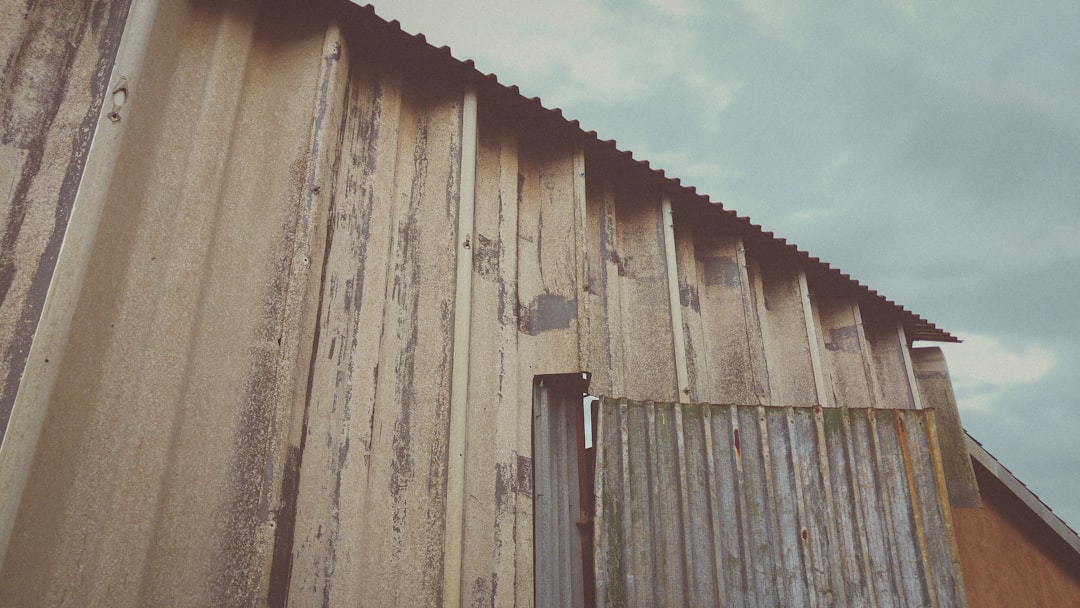 A haunting portrayal of an abandoned workshop, constructed from asbestos and corrugated iron, standing stoically against the backdrop of a gloomy and cold day. The sharp lines and angles of the workshop echo the passage of time, telling a silent story of industry faded into quiet desolation.