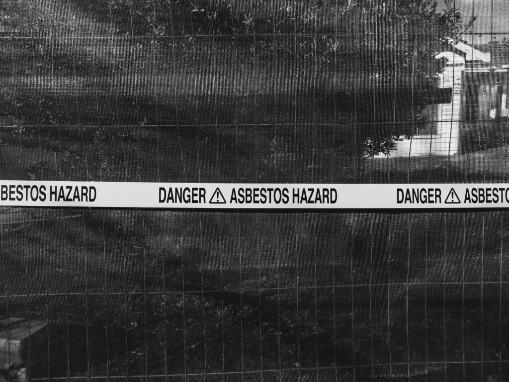 pexels photo 13364320 13364320 Black and white photo of an asbestos hazard warning sign on a fence.